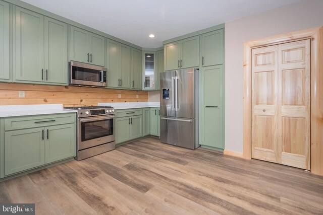 kitchen featuring stainless steel appliances, green cabinetry, light wood-type flooring, light countertops, and recessed lighting
