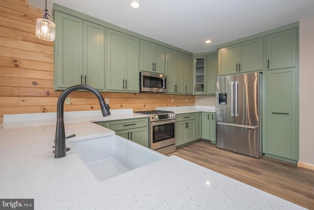 kitchen with stainless steel appliances, green cabinetry, a sink, recessed lighting, and pendant lighting