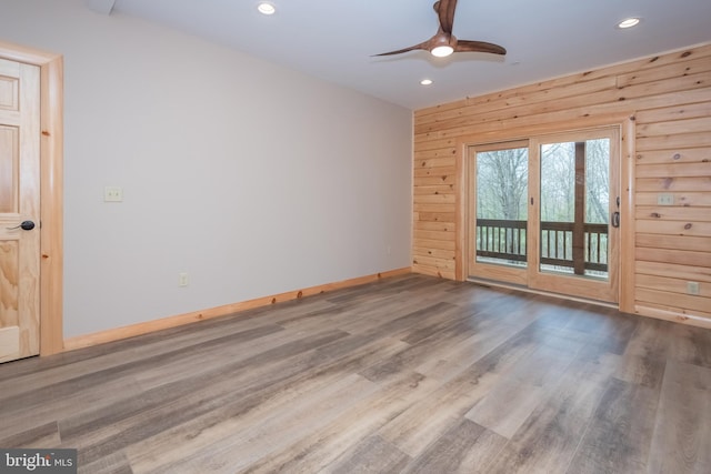 unfurnished room featuring recessed lighting, a ceiling fan, wood finished floors, baseboards, and wooden walls