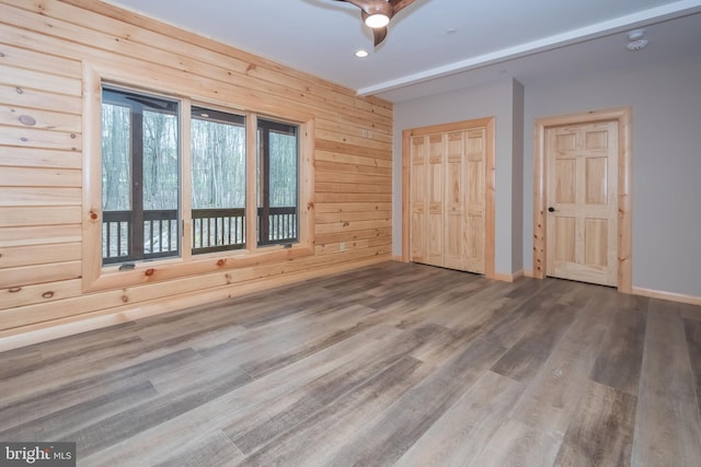 unfurnished bedroom with wood finished floors, baseboards, wooden walls, recessed lighting, and a ceiling fan