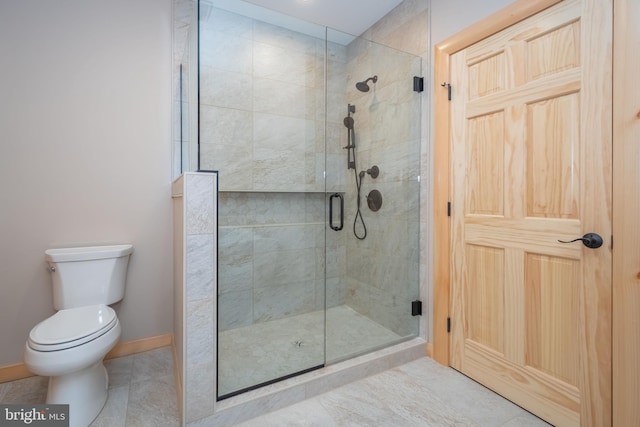 bathroom featuring a shower stall, toilet, and baseboards