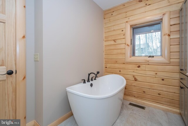 bathroom with a soaking tub and wood walls