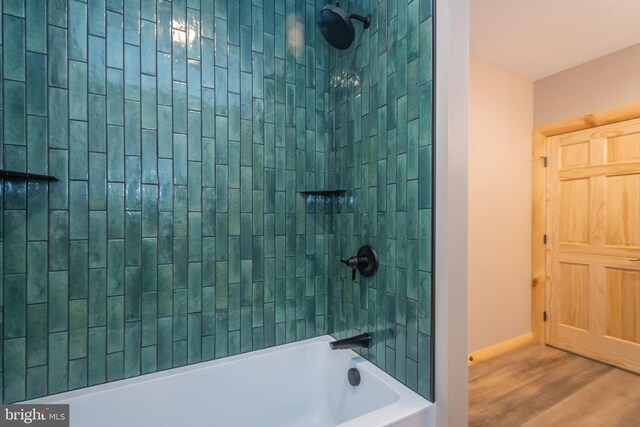 bathroom featuring wood finished floors, shower / bathtub combination, and baseboards