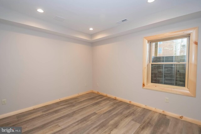 empty room featuring wood finished floors, baseboards, and recessed lighting