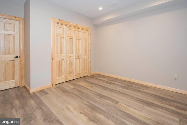unfurnished bedroom featuring baseboards, wood finished floors, a closet, and recessed lighting