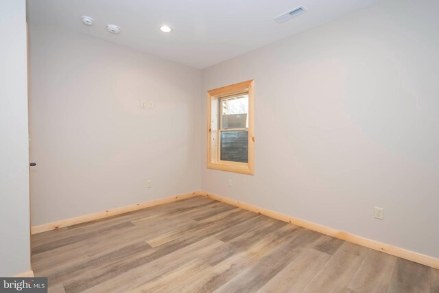 empty room featuring baseboards, light wood-style flooring, recessed lighting, and a smoke detector