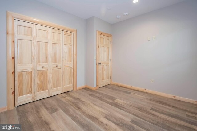 unfurnished bedroom featuring baseboards, wood finished floors, recessed lighting, and a closet