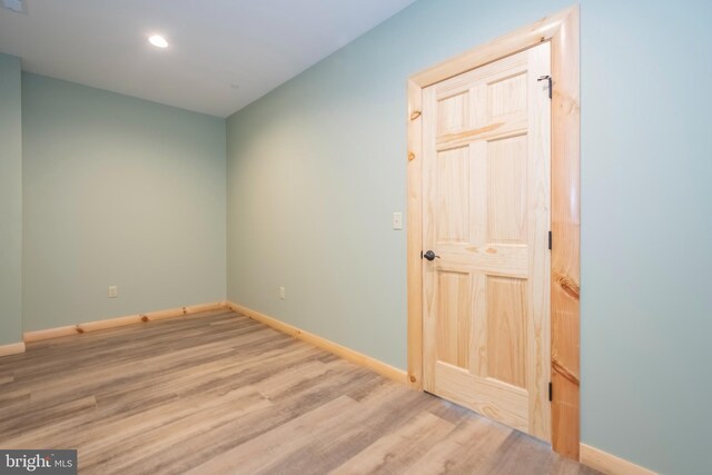 spare room with baseboards, wood finished floors, and recessed lighting