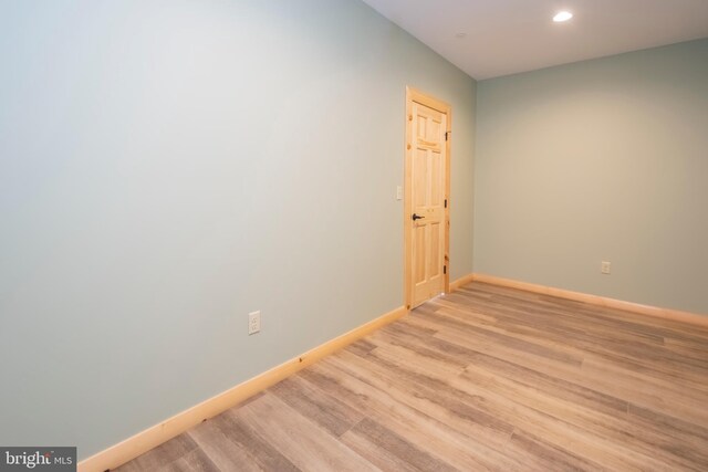 empty room featuring baseboards, light wood-type flooring, and recessed lighting