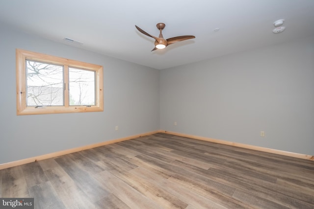 spare room with a ceiling fan, baseboards, wood finished floors, and a smoke detector