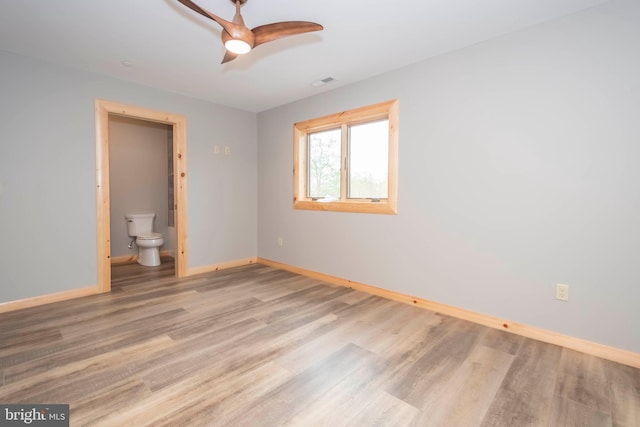 unfurnished bedroom with baseboards, wood finished floors, ensuite bathroom, and ceiling fan