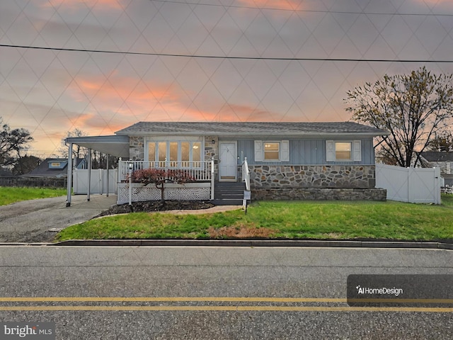 ranch-style house with fence, concrete driveway, an attached carport, stone siding, and a front yard