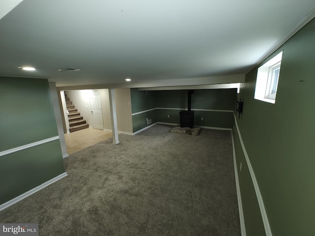 below grade area featuring stairs, a wood stove, carpet, baseboards, and recessed lighting