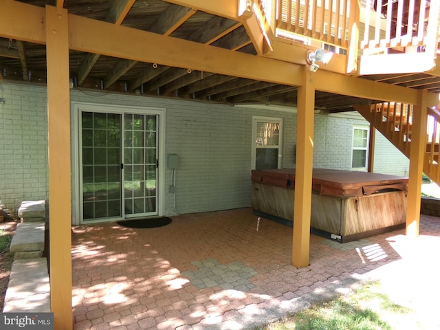 view of patio with a hot tub and a deck