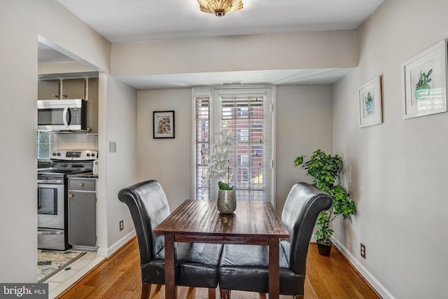 dining space featuring baseboards and light wood-style flooring