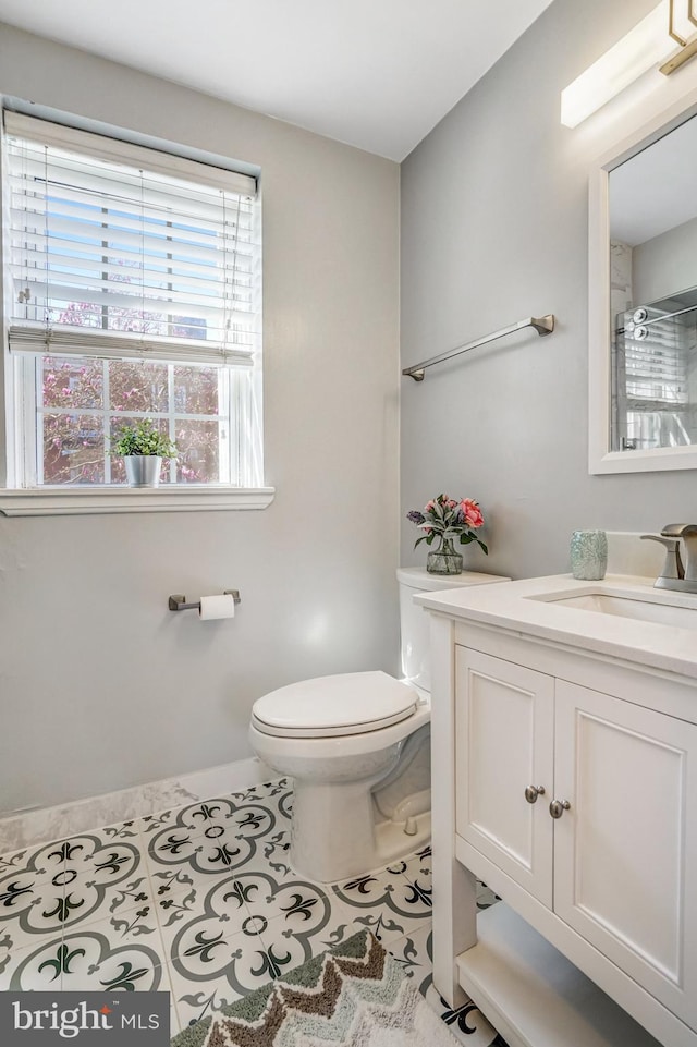 bathroom with walk in shower, baseboards, toilet, vanity, and tile patterned flooring