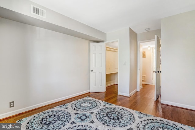 bedroom with baseboards, visible vents, and wood finished floors