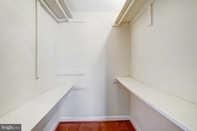 spacious closet with built in desk and wood finished floors