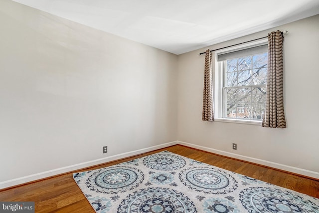 unfurnished room with baseboards and wood finished floors