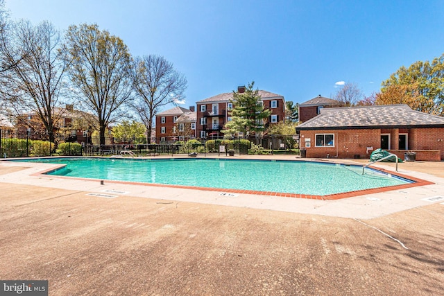 community pool featuring a residential view, fence, and a patio area