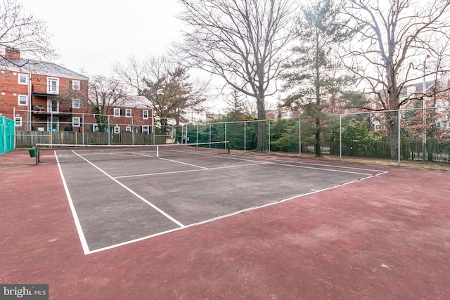 view of tennis court with community basketball court and fence