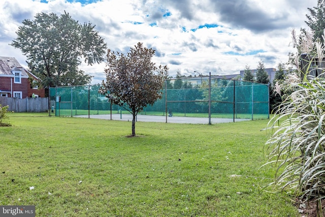 view of sport court with a lawn and fence
