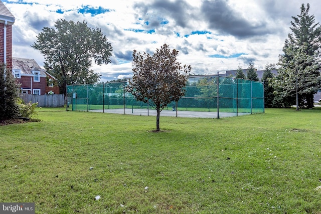 view of sport court with a yard and fence