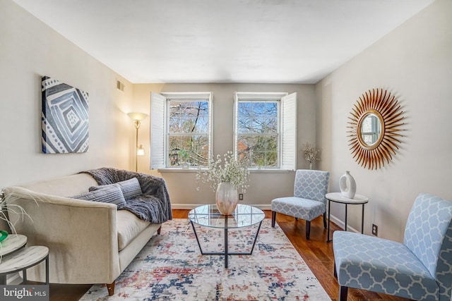 living area featuring baseboards, visible vents, and wood finished floors