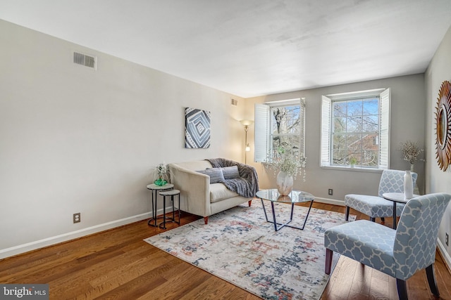 living area with baseboards, visible vents, and wood finished floors