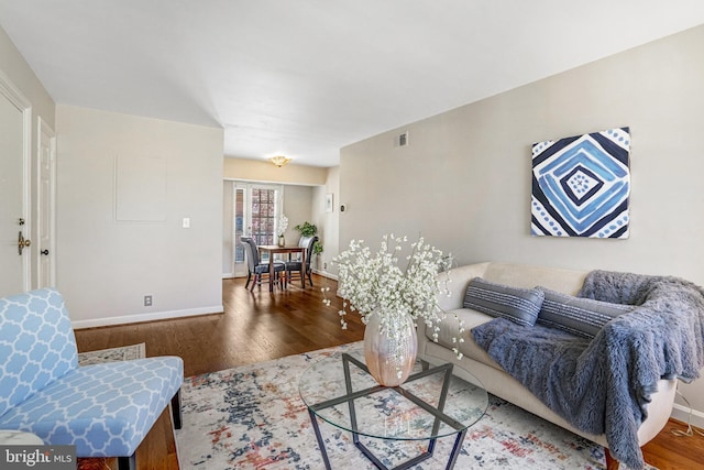 living area featuring visible vents, baseboards, and wood finished floors