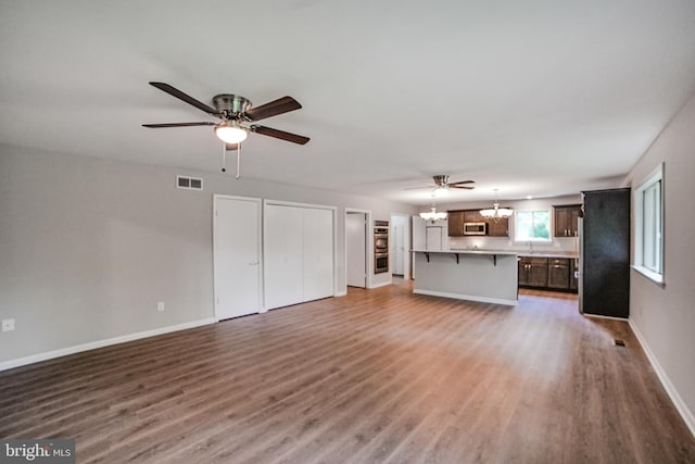 8012 Exodus Dr, Gaithersburg, MD 20882 - unfurnished living room featuring wood finished floors, a ceiling fan, a chandelier, and baseboards