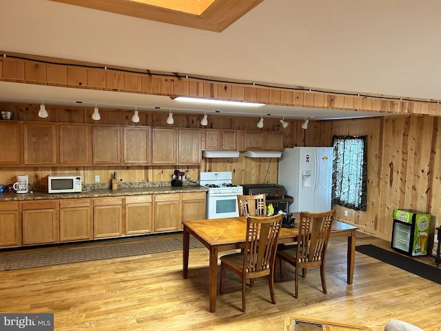 385 Elk Crk, Aaronsburg, PA 16820 - kitchen featuring light wood finished floors, wooden walls, under cabinet range hood, dark stone countertops, and white appliances