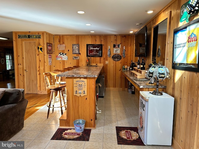 385 Elk Crk, Aaronsburg, PA 16820 - kitchen with light tile patterned floors, wooden walls, a breakfast bar, and recessed lighting