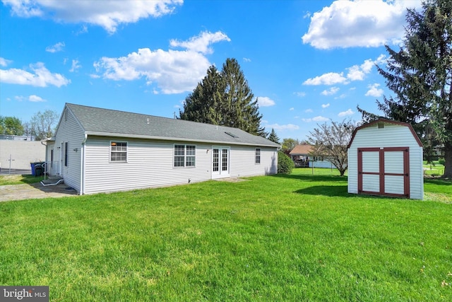 back of house featuring a lawn, an outbuilding, french doors, and a storage unit
