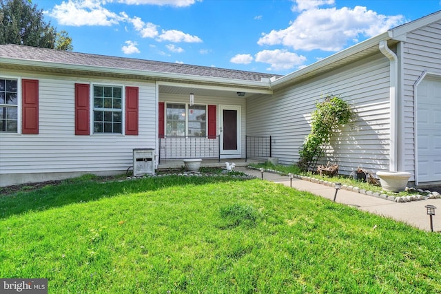 doorway to property with a yard, covered porch, and a garage