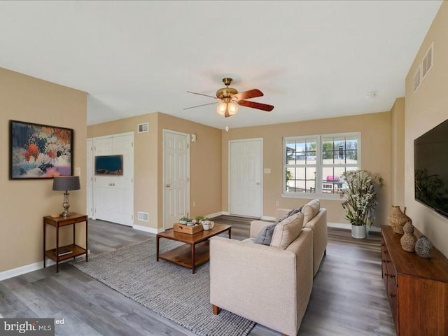 living area featuring baseboards, a ceiling fan, wood finished floors, and visible vents