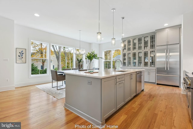kitchen featuring light countertops, a sink, gray cabinetry, and high quality appliances