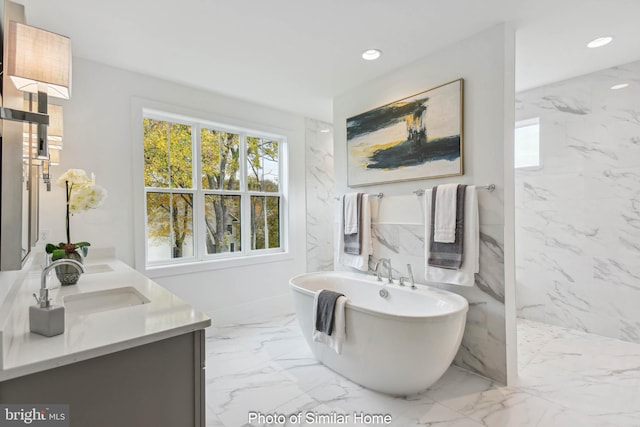 full bathroom with a sink, a wealth of natural light, a soaking tub, and marble finish floor