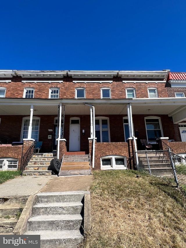 211 S Hilton St, Baltimore, MD 21229 - townhome / multi-family property featuring brick siding and a porch