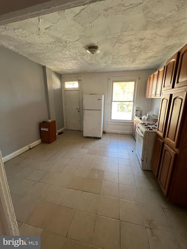 211 S Hilton St, Baltimore, MD 21229 - kitchen with light tile patterned floors, baseboards, white appliances, and a textured ceiling