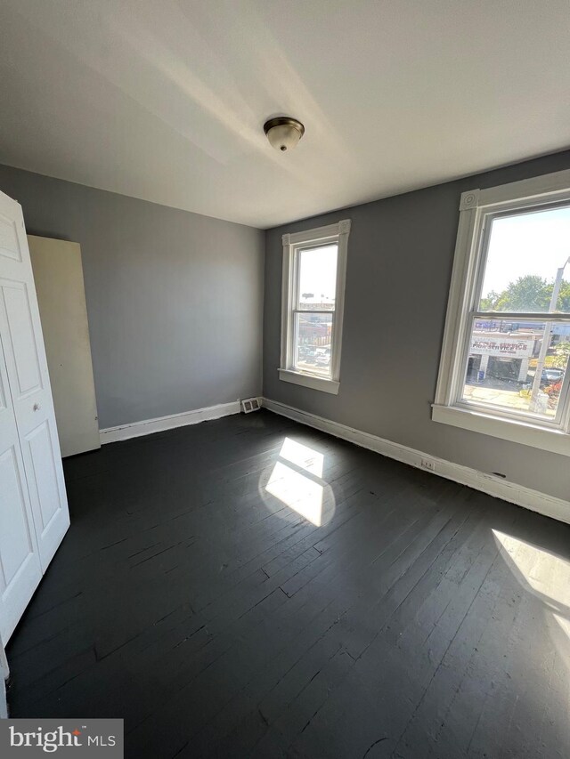 211 S Hilton St, Baltimore, MD 21229 - unfurnished bedroom with visible vents, baseboards, and dark wood-style floors