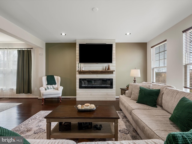 living room featuring baseboards, recessed lighting, wood finished floors, and a large fireplace