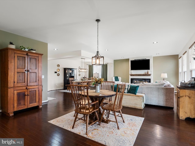 dining area featuring dark wood-style flooring, a glass covered fireplace, and recessed lighting
