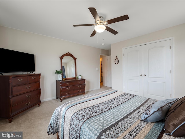 bedroom with light colored carpet, a closet, baseboards, and a ceiling fan