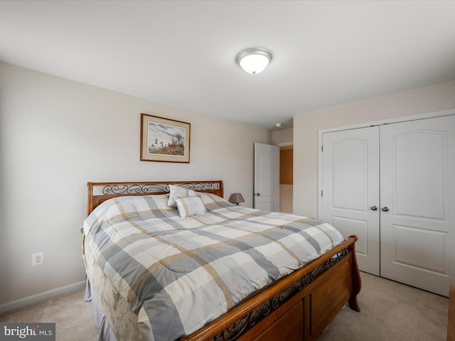 bedroom with light carpet, baseboards, and a closet