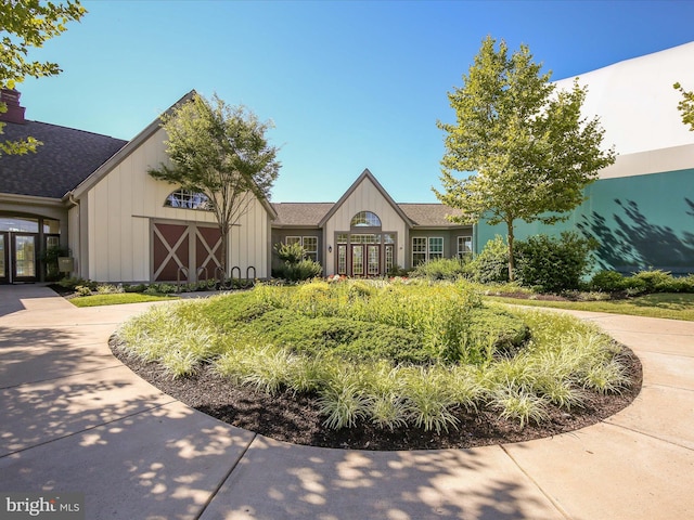 view of front of home with french doors, board and batten siding, a shingled roof, and a chimney