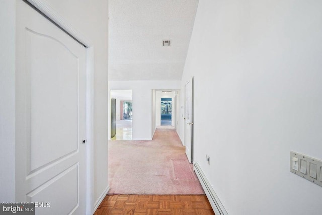 hall featuring carpet flooring, a textured ceiling, a baseboard radiator, baseboards, and visible vents