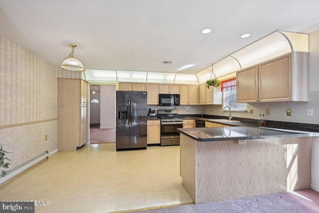 kitchen with wallpapered walls, dark countertops, a sink, black appliances, and light brown cabinetry