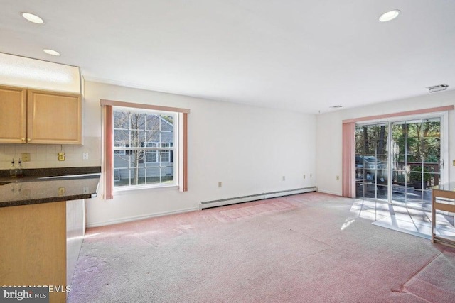 unfurnished living room featuring recessed lighting, a healthy amount of sunlight, light colored carpet, and baseboard heating