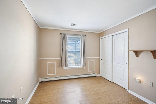 unfurnished bedroom with crown molding, baseboards, a baseboard heating unit, and wood finished floors